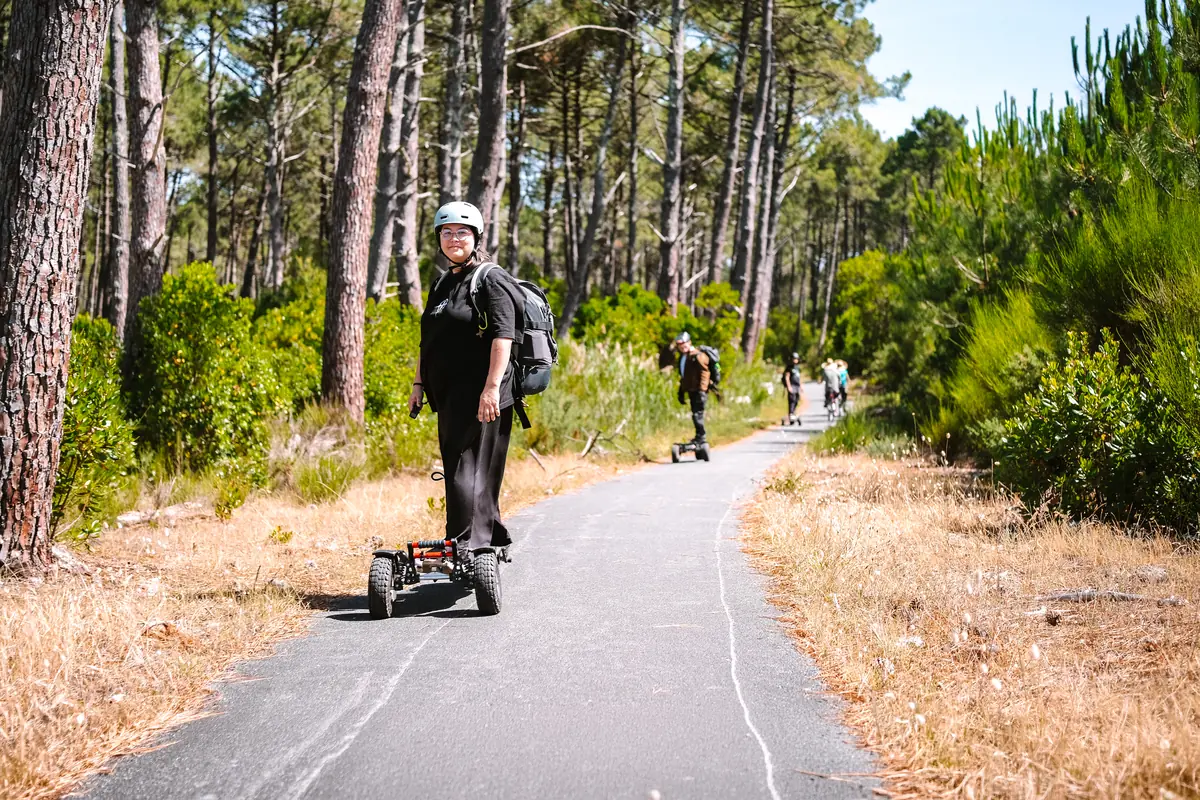 Helmeted rider on her Stern' on a narrow road through a pine forest, other riders behind