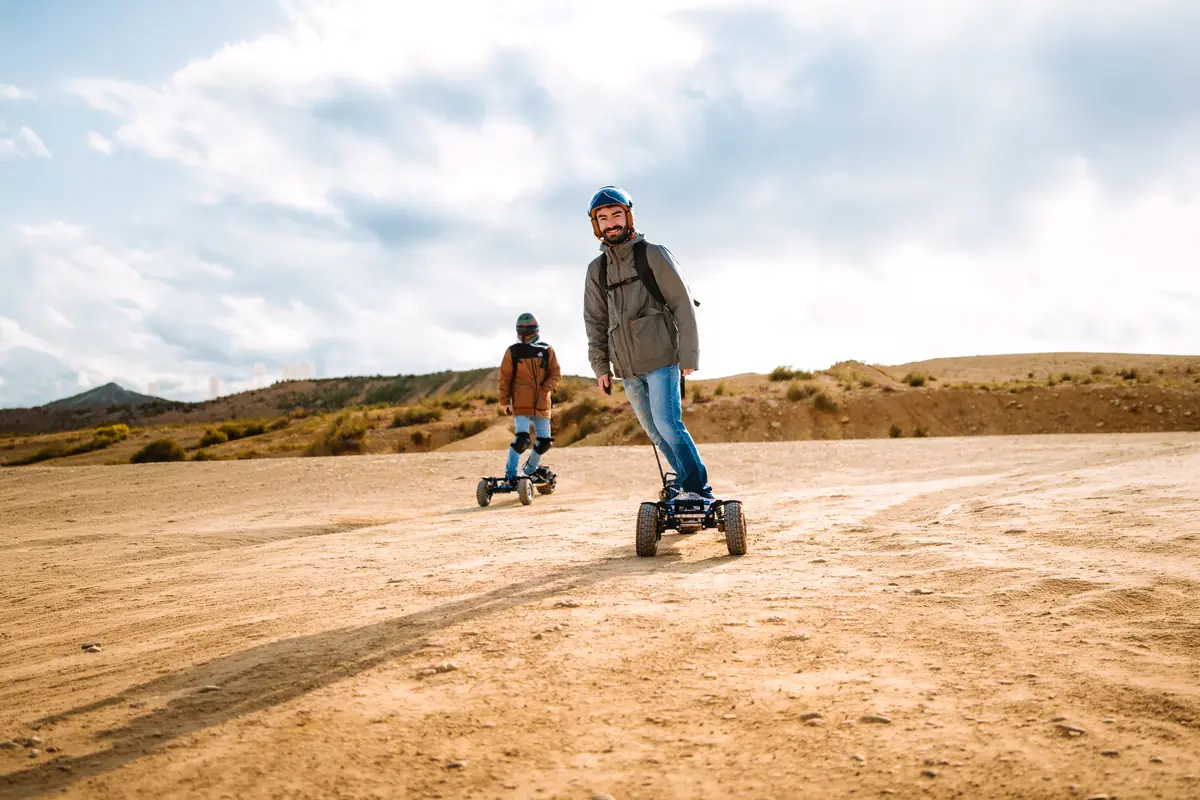 Two riders on a wide plateau of packed earth, under a cloudy sky