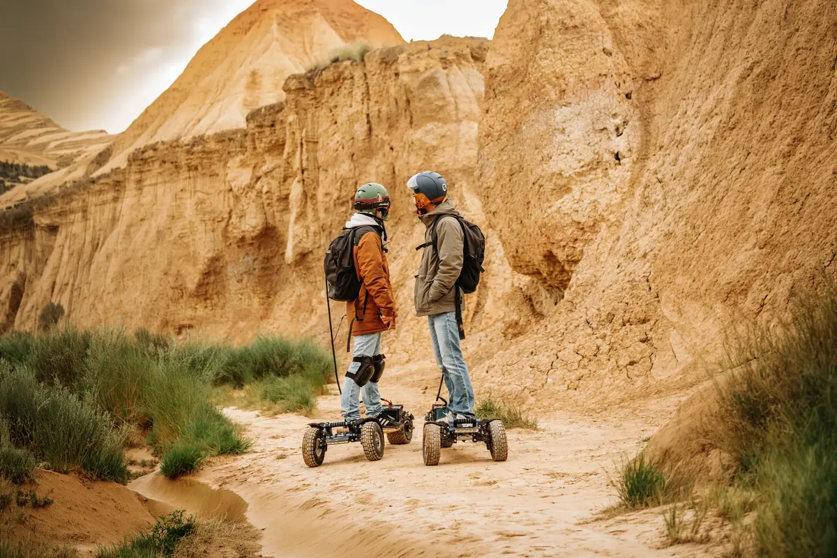 Two helmeted riders on their Stern' boards at the bottom of an ochre sand canyon