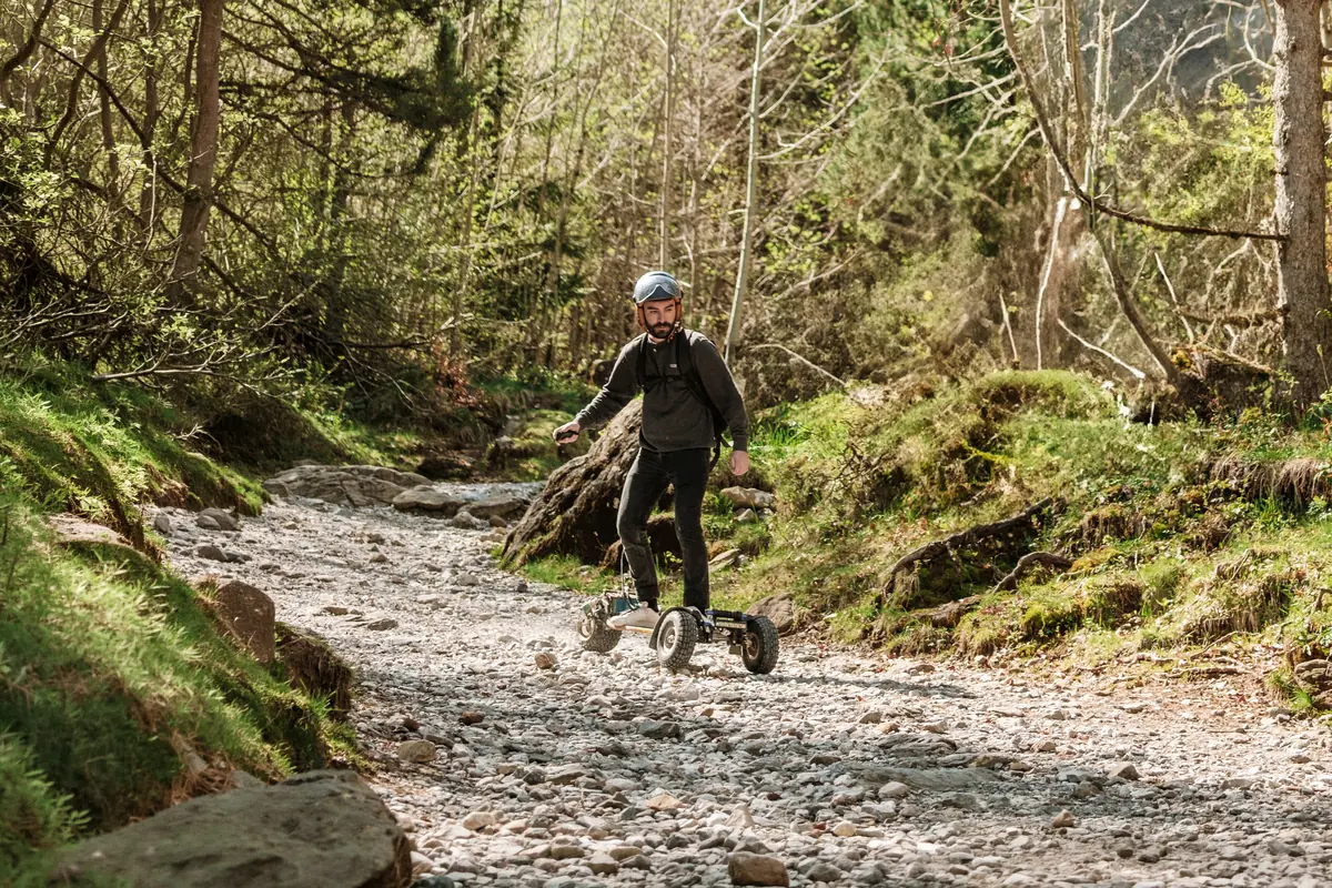 Helmeted rider riding a Stern' down a stony stream bed in the forest